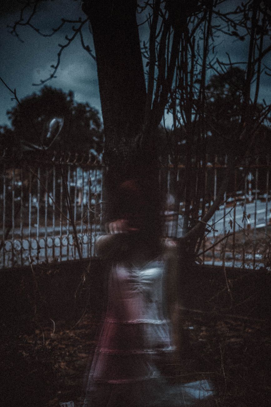 anonymous mysterious ghost woman standing in dark forest at night